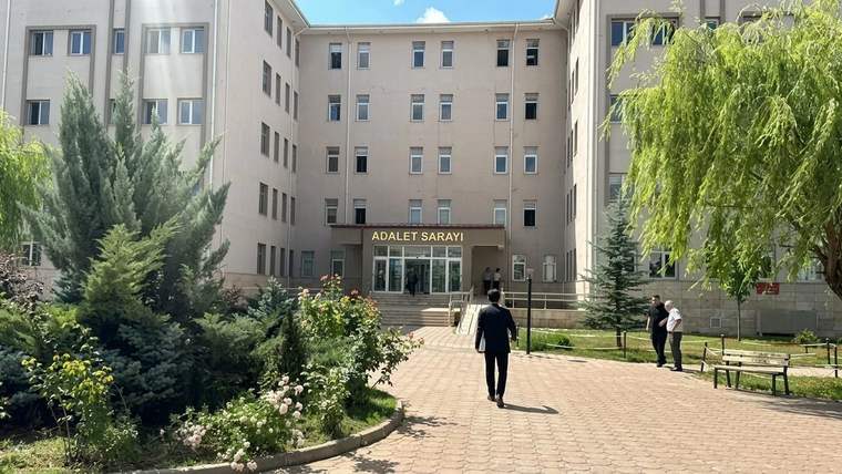 Girişinde “ADALET SARAYI” yazan binanın önünde yürüyen insanlar ve ağaçlarla çevrili avlu görülüyor.