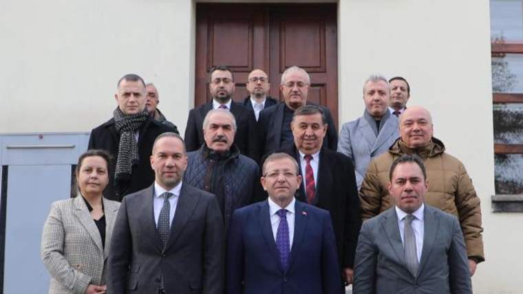 Kars Valiliği tabelası önünde, takım elbiseli ve montlu 13 kişi bina girişinde yan yana duruyor.