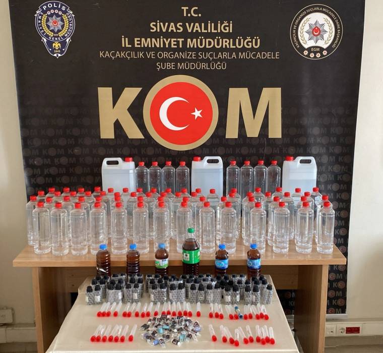 Üzerinde KOM yazılı bir arka planda, çeşitli boyutlarda şişeler ve alkol üretim kitleri sergileniyor.