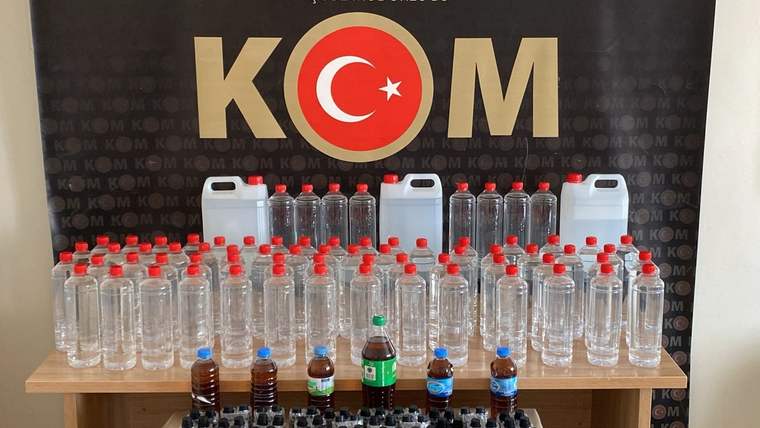 Üzerinde KOM yazılı bir arka planda, çeşitli boyutlarda şişeler ve alkol üretim kitleri sergileniyor.