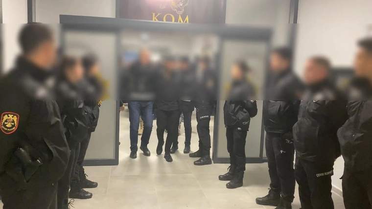 KOM ekipleri, gözaltına alınan bir kişiyi koridor boyunca götürüyor.