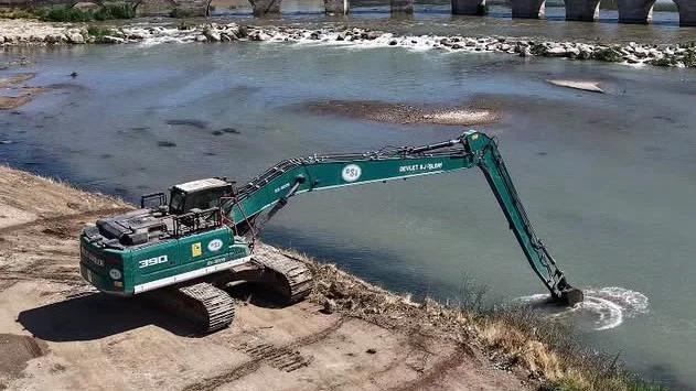 Kızılırmak Nehri kıyısında çalışan bir ekskavatör, suyun içinden malzeme alıyor.