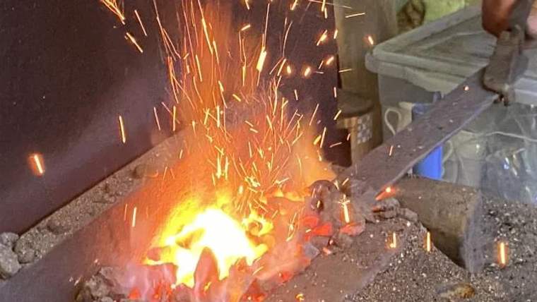Ateşin etrafında kıvılcımlar saçan bir demirci ocağı, sıcak metalin eritildiği bir atölye.