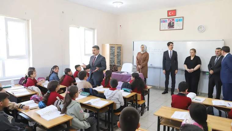 Sınıfta, öğretmen ve öğrencilerin bulunduğu bir grup, Milli Eğitim Müdürü ile sohbet ediyor.
