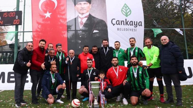 Şampiyonluk kupası ile poz veren futbol takımı, arka planda Atatürk'ün portresi ve Türk bayrağı var.