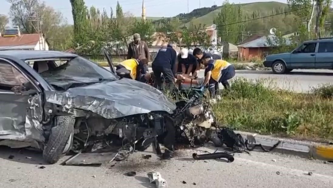 Ön kısmı ağır hasar almış otomobilin yanında, yol kenarında sedyeye müdahale eden kişiler görülüyor.