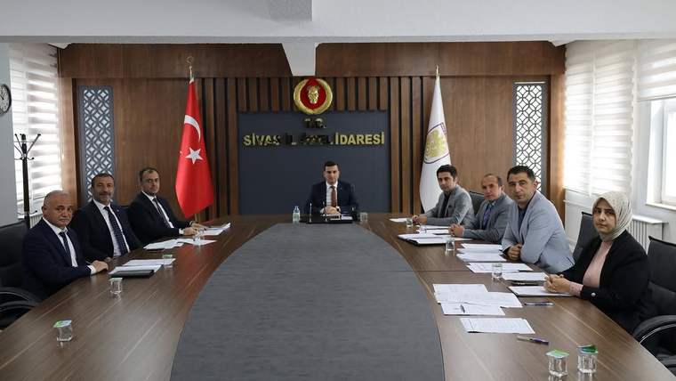 Sivas İl Özel İdaresi yazılı salonda, uzun masa çevresinde toplantı yapan dokuz kişi ve Türk bayrağı görülüyor.