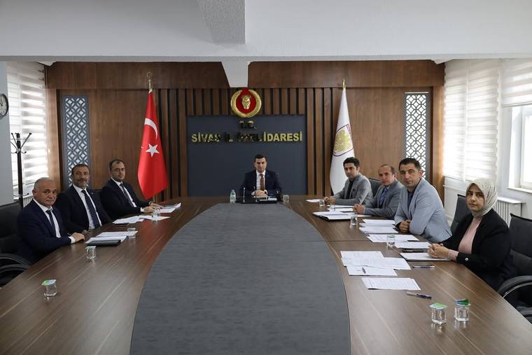 Sivas İl Özel İdaresi yazılı salonda, uzun masa çevresinde toplantı yapan dokuz kişi ve Türk bayrağı görülüyor.