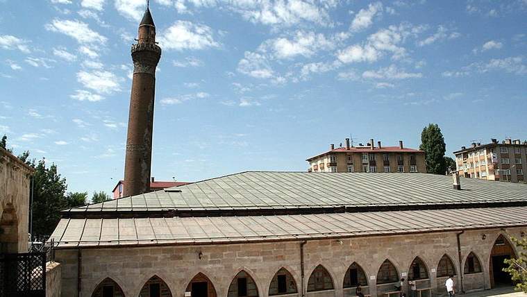Sivas Ulu Cami'nin dış görünümü, yanında bir minare ve çevresinde binalar yer alıyor.