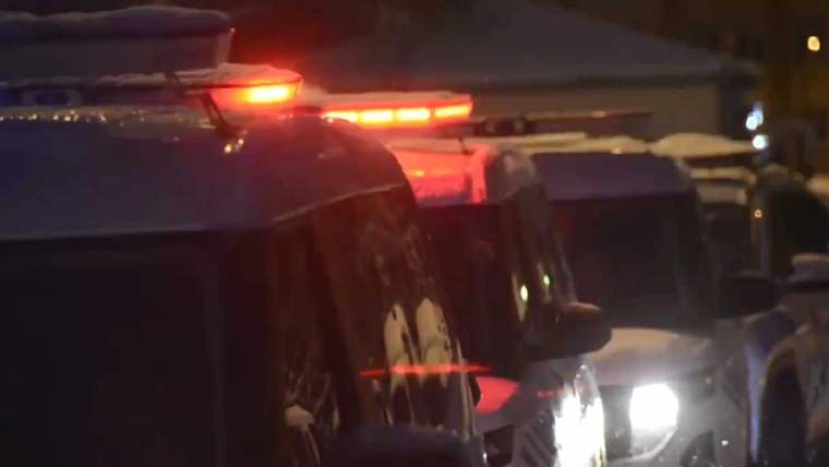 Kırmızı ışıkları yanan birkaç polis aracı, karla kaplı bir alanda duruyor.