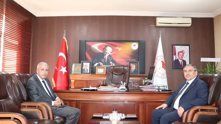 Sivas Tarım Orman Müdürlüğü'nde iki kişi, masanın önünde oturuyor. Arka planda Türk bayrağı ve Atatürk'ün resmi var.