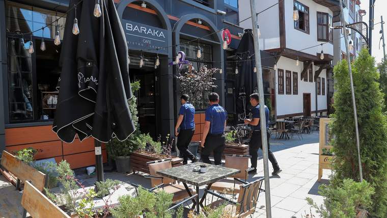 Zabıta ekipleri, bir kafe önünde yürüyerek kaldırım işgalleriyle mücadele ediyor.