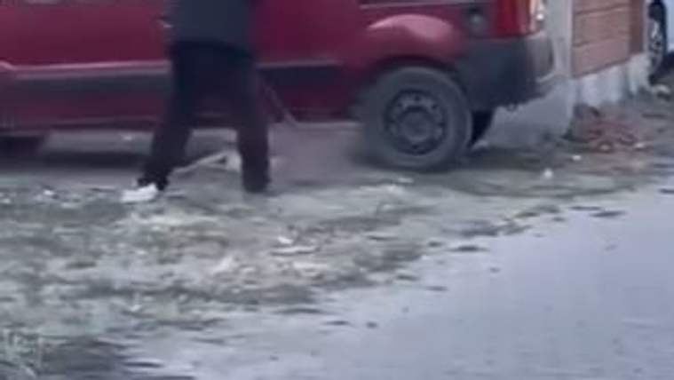 Kırmızı bir aracın yanında, buzlu zeminde yürüyen ve yüzü görünmeyen bir kişi görülüyor.