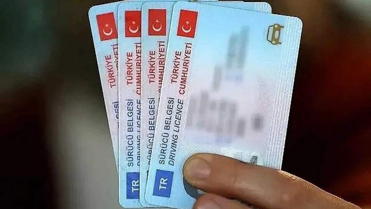 Bir kişinin elinde dört adet eski tip sürücü belgesi bulunuyor.