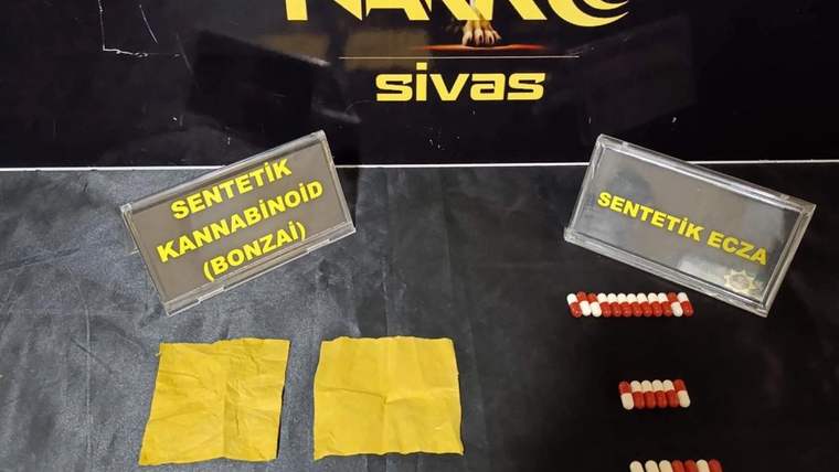 Sarı paketler ve beyaz-kırmızı haplar, narkotik operasyonu için sergileniyor.
