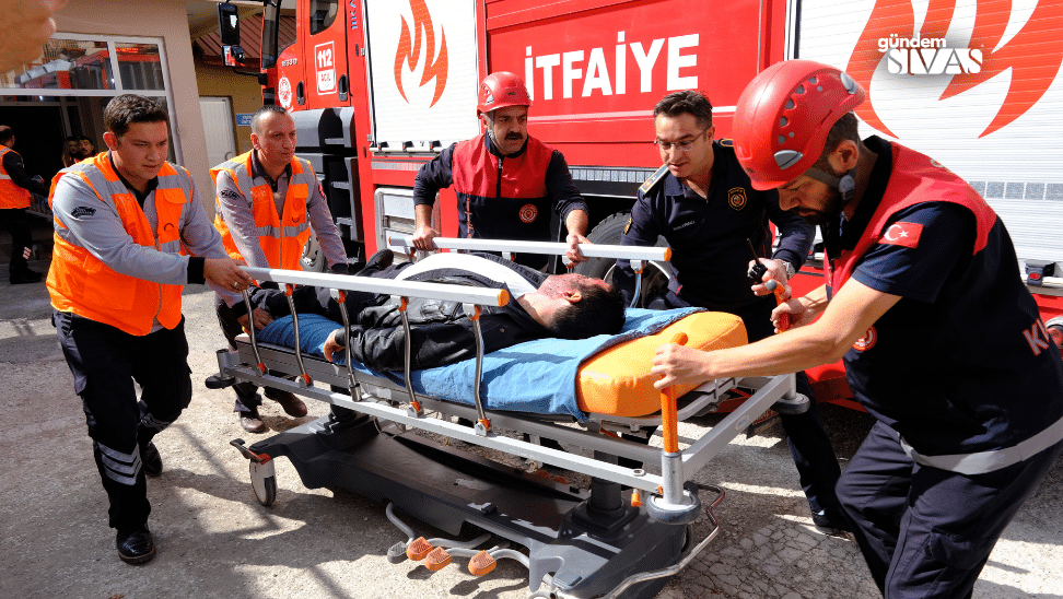 İtfaiye ve sağlık ekipleri, yaralı bir kişiyi sedyeye alarak taşımakta.