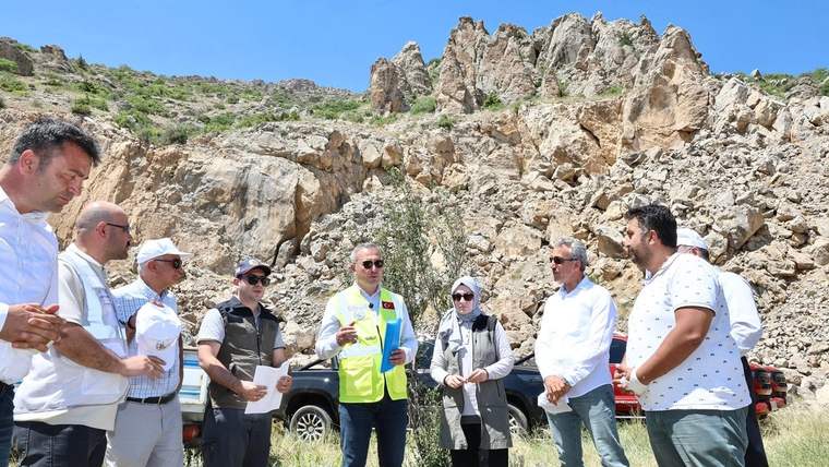 Bir grup insan, taş ocağının önünde toplanmış, bazıları belgeleri inceliyor.