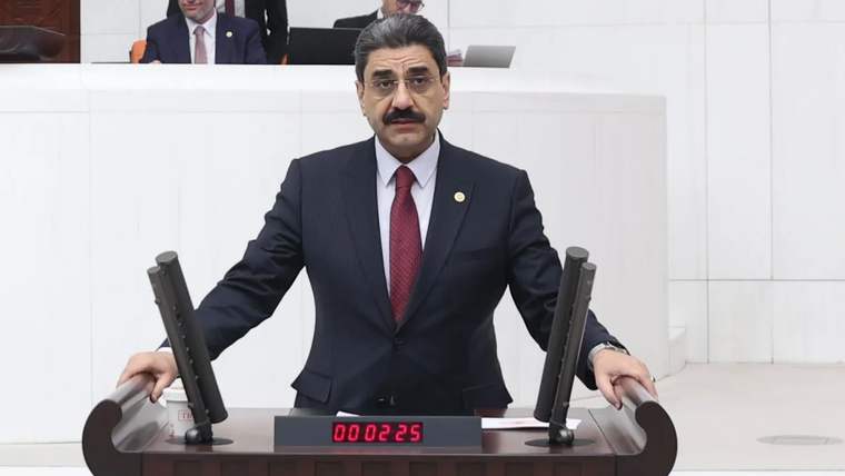 Kürsüde konuşan bir kişi, arka planda başka insanlar görünüyor.