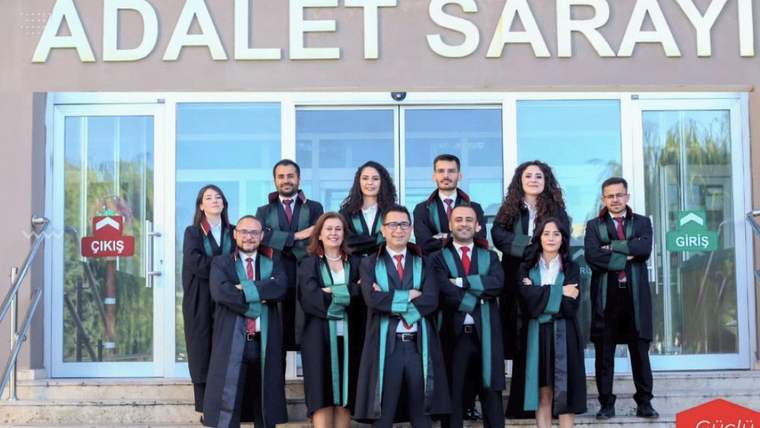 Adalet Sarayı girişinde, üzerinde cübbe bulunan bir grup kişi basamaklarda birlikte duruyor.