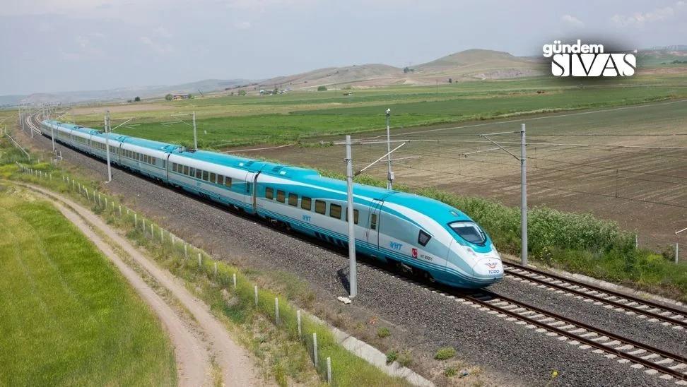 Mavi-beyaz renkte yüksek hızlı tren, tarım arazileri arasında raylar üzerinde ilerliyor.
