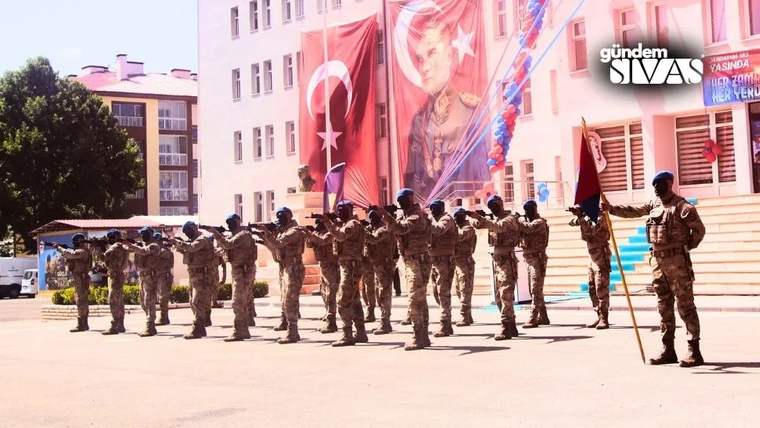 Askeri kıyafet giymiş jandarma personeli, tören alanında silahlarını havaya kaldırarak selam duruyor.