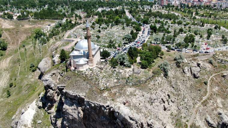 Bir tepenin üzerinde yer alan Ay Yıldız Camii, çevresinde mezarlık ve ağaçlar ile birlikte görünmekte.