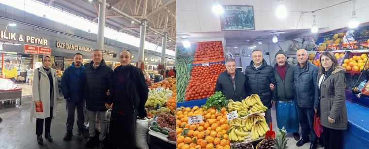Bir pazar yerinde, sebze ve meyve tezgahlarının önünde duran dört kişi.