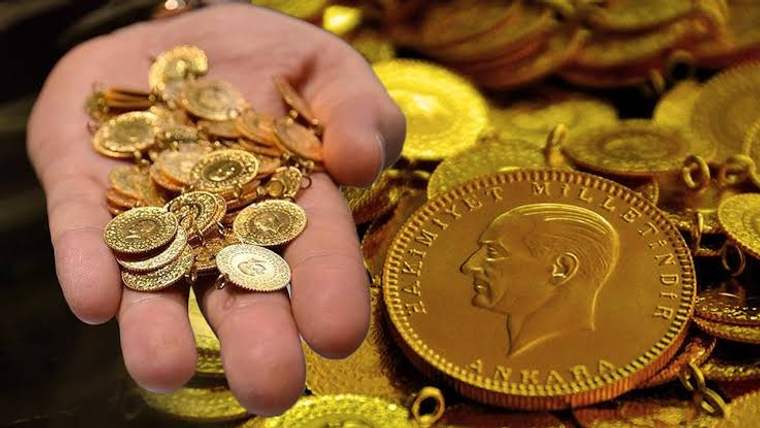 Bir elde çeşitli altın sikkeler, yanında büyük madalyon ve zincir parçaları bulunuyor.
