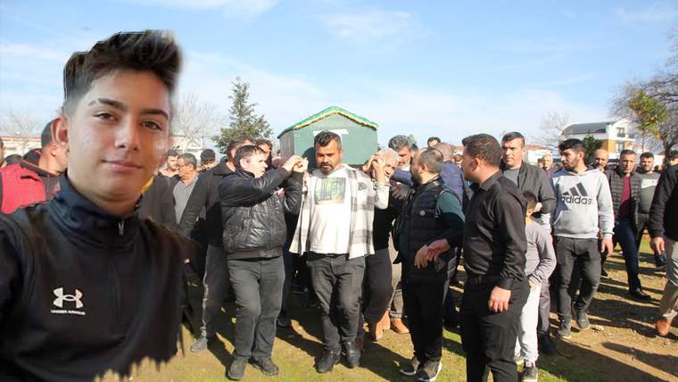 Önde siyah montlu genç bir kişinin portresi, arka planda açık alanda yürüyen kalabalık erkek grubu görülüyor.