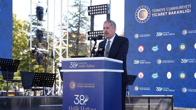 Açık hava sahnesinde kürsüde konuşan bir kişi, arkasında Ticaret Bakanlığı ve Ahilik Haftası panosu bulunuyor.
