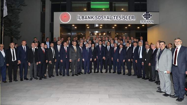 İLBANK Sosyal Tesisleri girişinde, takım elbiseli çok sayıda kişi birlikte poz veriyor.