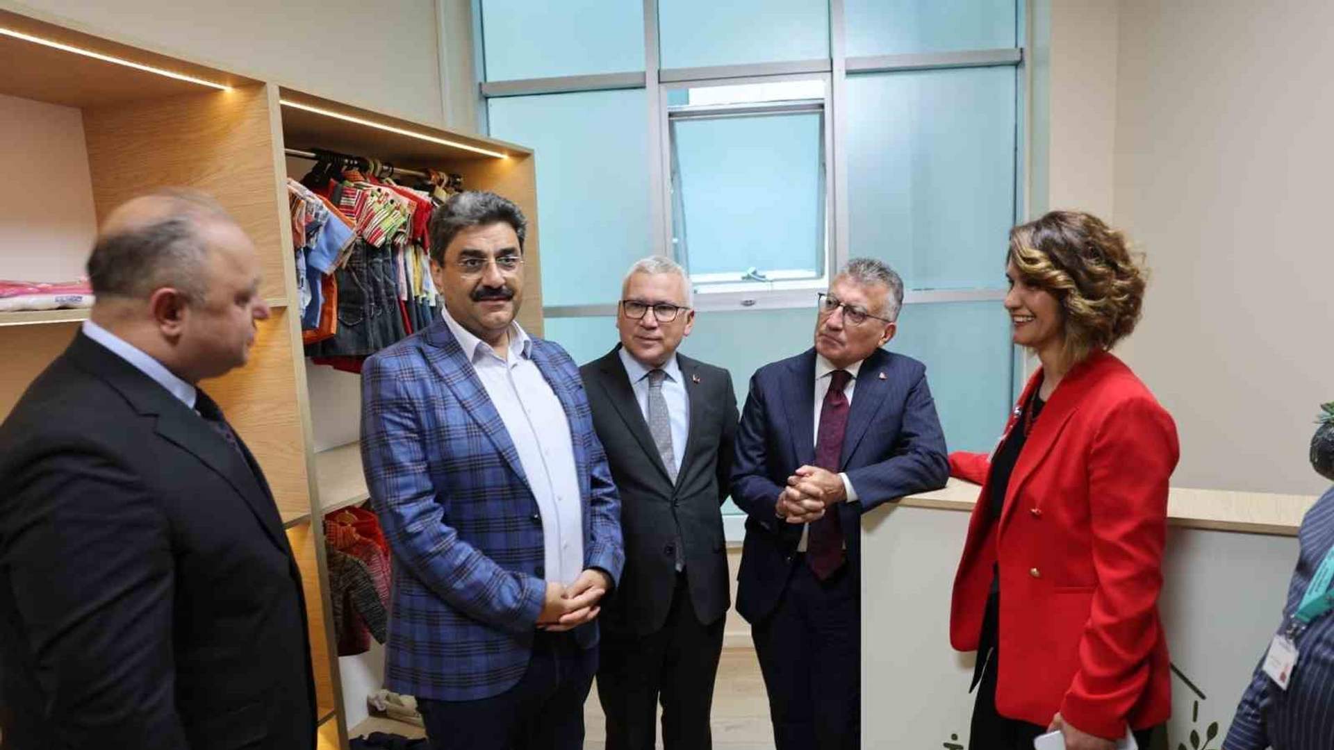 Giysi dolabının önünde, biri kırmızı ceketli beş kişi yan yana duruyor.