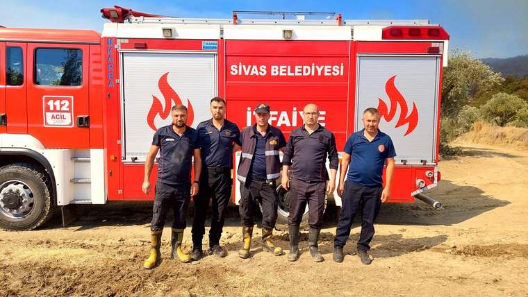 Sivas Belediyesi itfaiyesine ait bir araç, ormanlık alanda duruyor; önünde beş itfaiye personeli yer alıyor.