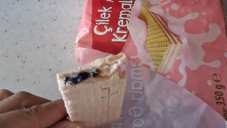 Bir el, çilekli gofretin iç kısmında bulunan yabancı maddeyi gösteriyor.