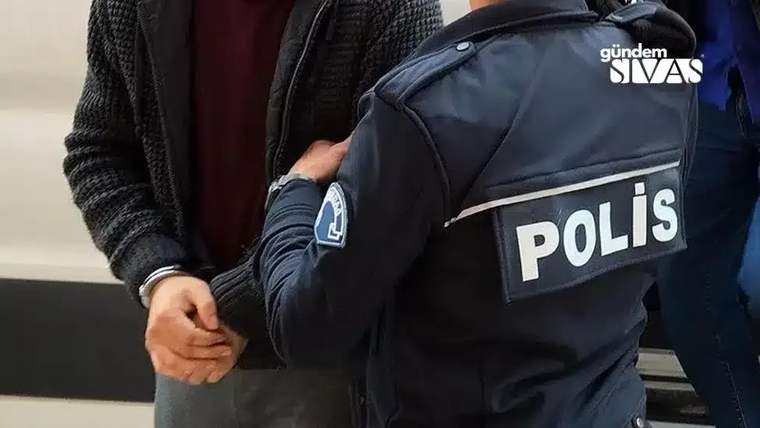 Kolları kelepçeli bir kişi, polis memurunun yanında duruyor.