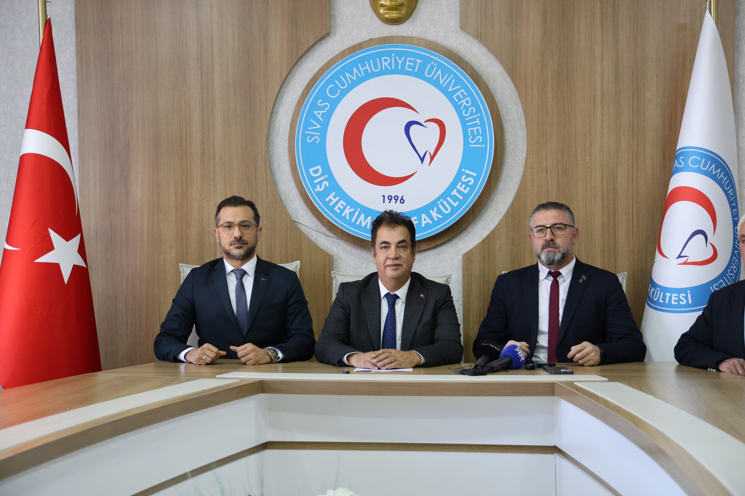 Sivas Cumhuriyet Üniversitesi Diş Hekimliği Fakültesi'nde üç kişi, masada oturuyor.