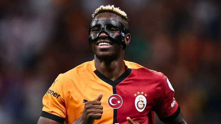 Sarı-kırmızı forma giymiş bir futbolcu, gülümseyerek poz veriyor.