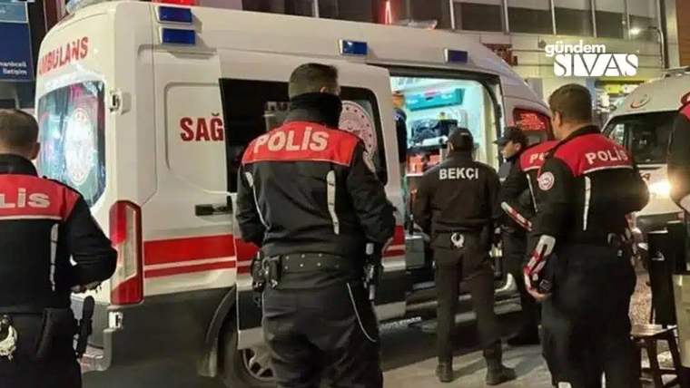 Bir ambulansın yanında, sırtlarında POLİS yazan görevliler ve üzerinde BEKÇİ yazan bir kişi duruyor.