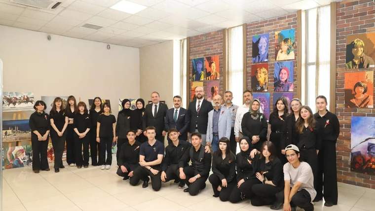 Sergi salonunda, duvarlardaki portre ve tabloların önünde siyah giyimli kalabalık bir grup poz veriyor.