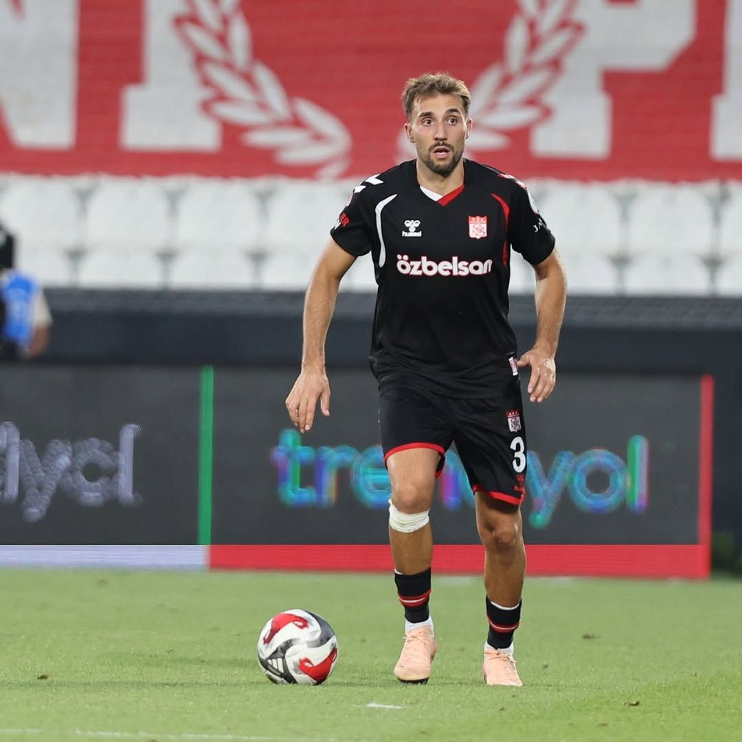 Siyah formalı, üzerinde 3 numarası bulunan futbolcu, topun yanında sahada ilerlerken görülüyor.