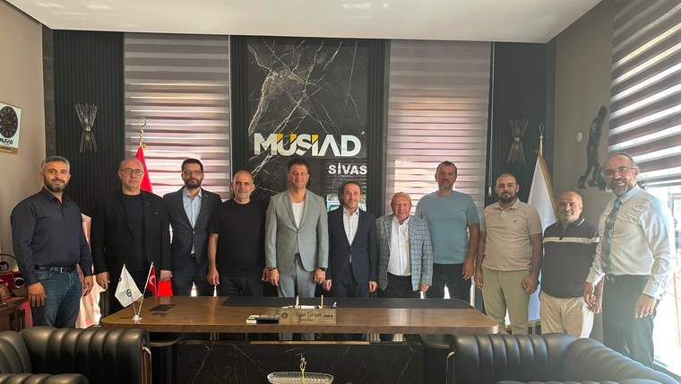 MÜSİAD Sivas yazılı duvar önünde, bir masa arkasında yan yana duran dokuz kişi görülüyor.