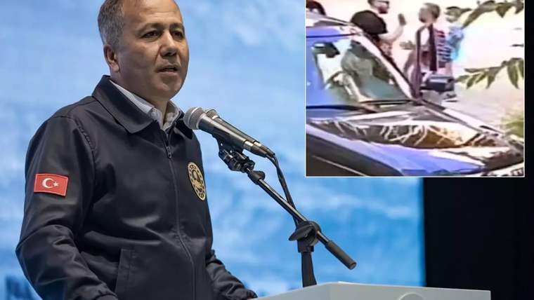 Türk bayrağı armalı mont giyen bir kişi kürsüde konuşuyor; sağ üstte araç yanında duran insanlar görülüyor.