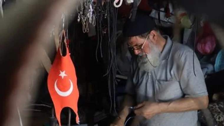 Bir kişi, dükkân içinde çalışırken Türk bayrağı asılı duruyor.