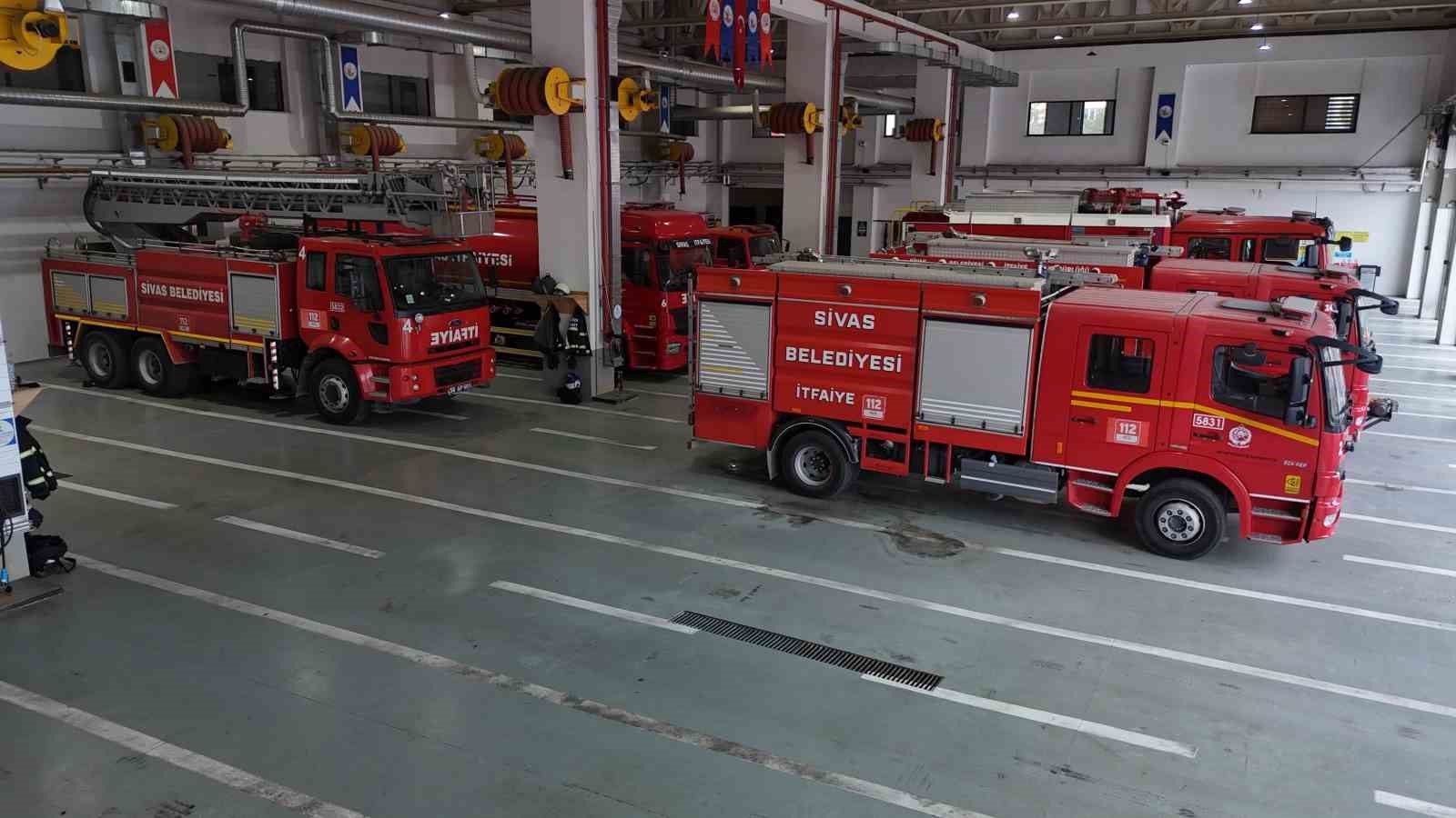 İtfaiye istasyonunun garajında, üzerinde Sivas Belediyesi İtfaiye yazan kırmızı araçlar sıralanıyor.