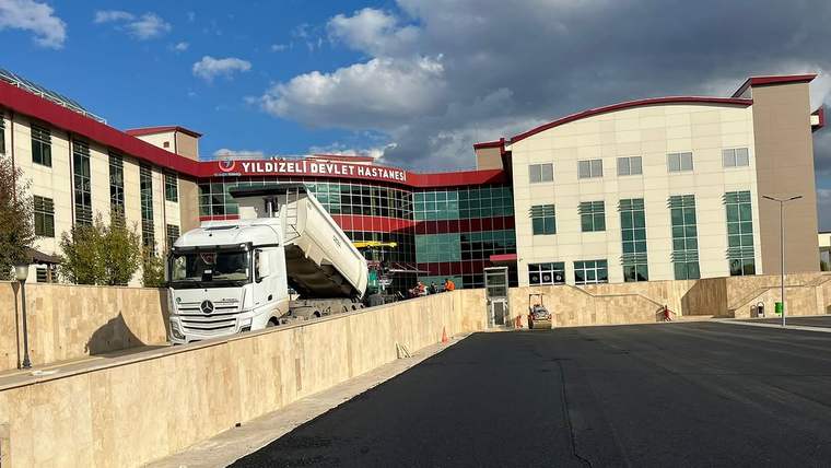 Yıldızeli Devlet Hastanesi önünde asfalt çalışması yapan bir kamyon, hastane binasının önünde duruyor.