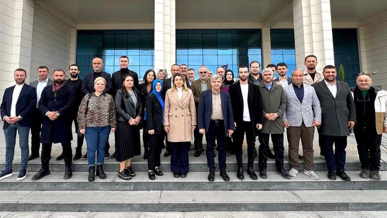 Bina girişindeki merdivenlerde, aralarında kadınların da bulunduğu kalabalık bir grup birlikte poz veriyor.