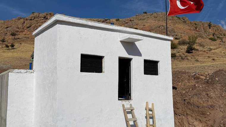 Beyaz bir su deposu, önünde merdiven ve Türk bayrağı dalgalanıyor.