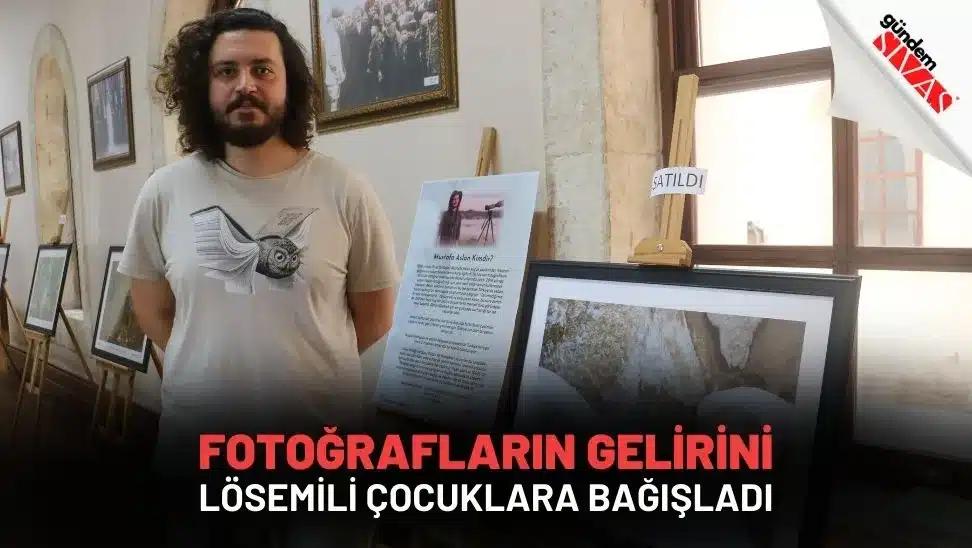 Bir adam, yanında fotoğrafların sergilendiği bir alanda duruyor.
