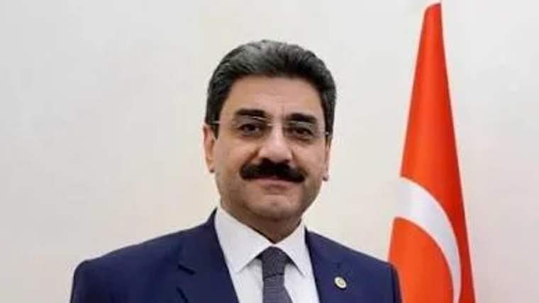 Kürsüde konuşan bir kişi, arka planda Türk bayrağı görünmekte.
