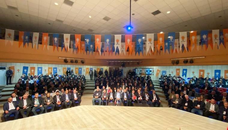 Toplantı salonunda, duvar ve tavandaki parti flamaları önünde oturan kalabalık bir grup görülüyor.